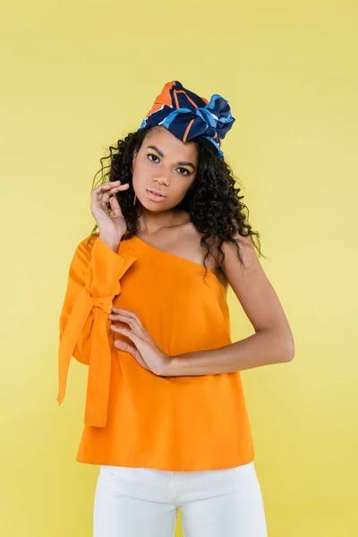 Pretty african american woman in kerchief posing while looking at camera isolated on yellow — Stock Photo