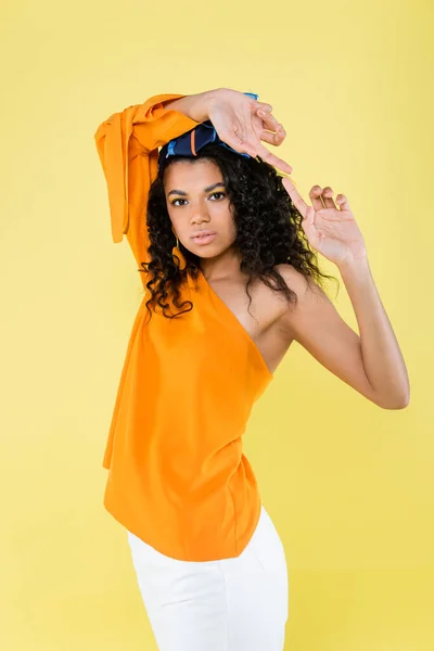 Femme afro-américaine bouclée avec épaule nue posant isolé sur jaune — Photo de stock