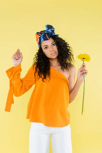 African american woman with bare shoulder holding flower isolated on yellow — Stock Photo