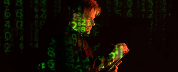 Joven programador escribiendo en portapapeles cerca del código de la computadora que refleja en el fondo negro, banner - foto de stock