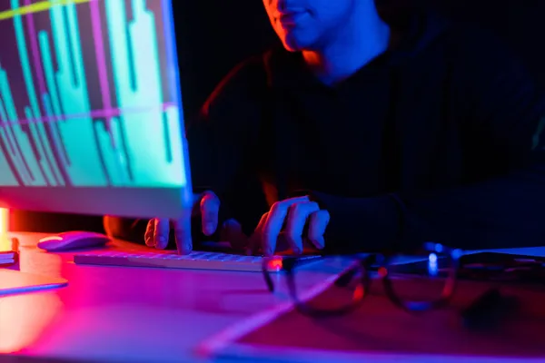 Vue recadrée du programmeur à l'aide d'un ordinateur avec des cartes reflétant près des lunettes sur la table sur fond noir — Photo de stock