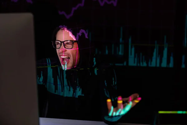 Angry hacker with charts reflection using computer on black background — Stock Photo