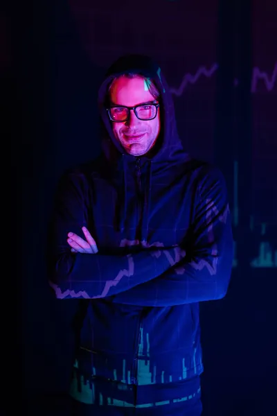 Hacker in eyeglasses with charts reflection looking at camera on black background — Stock Photo