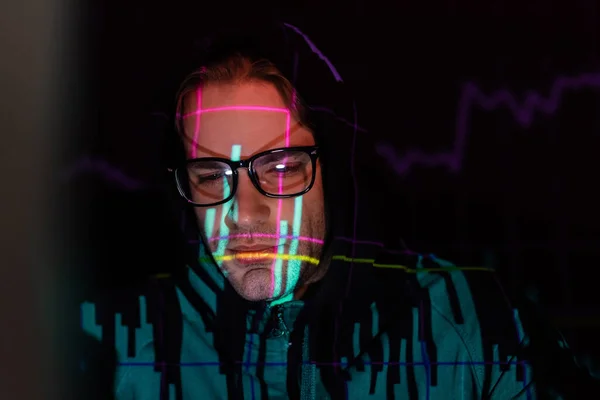 Displeased hacker with charts reflection looking down on black background — Stock Photo