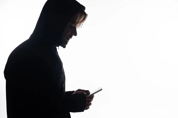 Vista lateral del hacker utilizando teléfono inteligente aislado en blanco - foto de stock