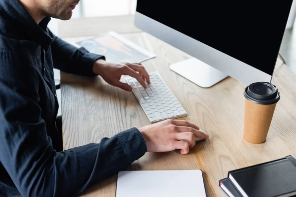 Vista ritagliata del programmatore utilizzando il computer vicino alla tazza di carta e notebook in ufficio — Foto stock