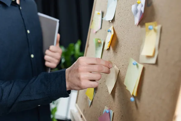 Cropped view of programmer pinning sticky notes on board — Stock Photo