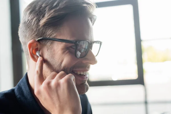 Desarrollador alegre en auriculares escuchando música en la oficina - foto de stock