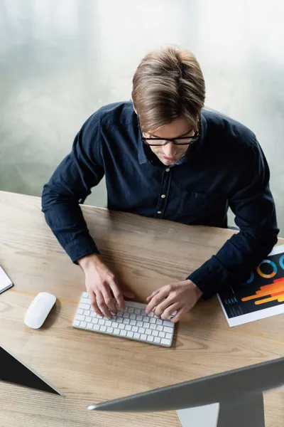 Overhead view of programmer typing on keyboard near computers on table — Stock Photo