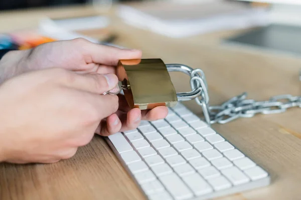 Cropped view of programmer holding padlock near keyboard in office — Stock Photo