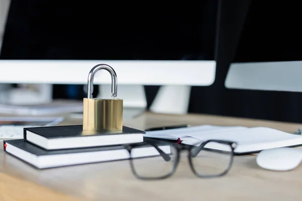 Vorhängeschloss an Notebooks in der Nähe von Brillen und Computern im Büro — Stockfoto