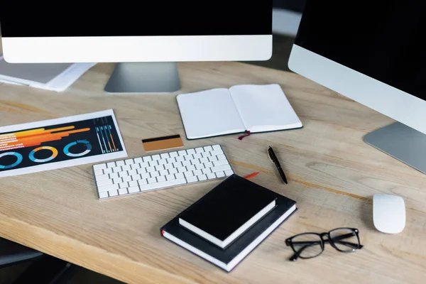 Kreditkarten in der Nähe von Computern und Notebooks auf Arbeitstisch im Büro — Stockfoto