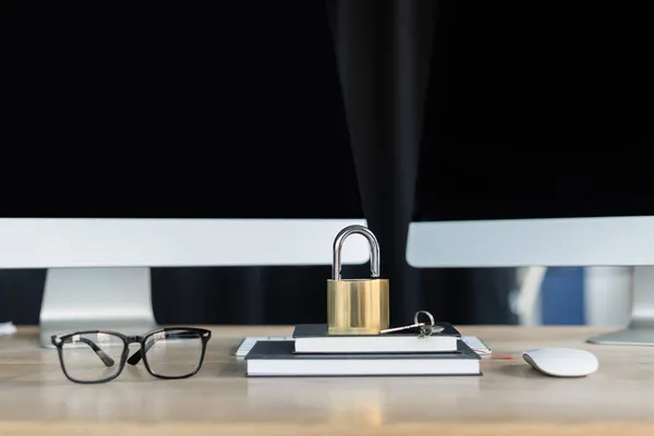 Vorhängeschloss auf Notebooks neben Brillen und Computer auf dem Tisch im Büro — Stockfoto