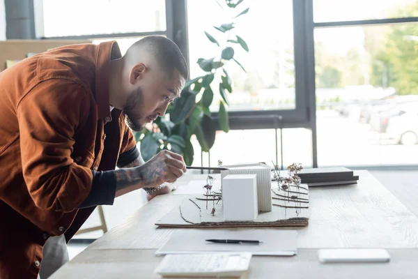 Asiatique ingénieur pointant avec crayon à maison modèles tout en travaillant dans bureau d'architecture — Photo de stock