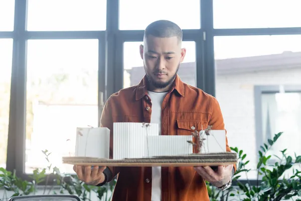 Asian architect holding construction project with house models in office — Stock Photo