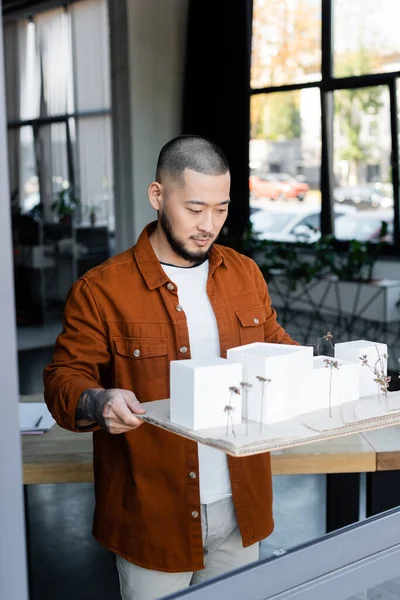 Asiatischer Architekt hält Hausmodelle, während er im Architekturbüro arbeitet — Stockfoto