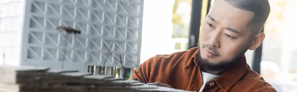 Asian architect looking at blurred house model while working on project, banner — Stock Photo