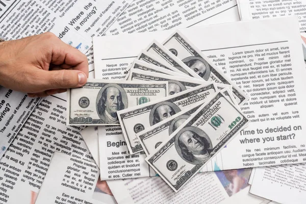 QUIIV, UCRÂNIA - NOVEMBRO 1, 2021: visão parcial do homem que detém notas de dólar perto de jornais impressos — Fotografia de Stock