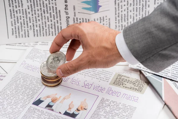 KYIV, UKRAINE - NOVEMBER 1, 2021: cropped view of man holding bitcoin near printed newspaper with lettering, translation: free life but risky — Stock Photo