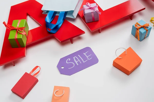 Vista ad alto angolo di vendita tag vicino a minuscole borse della spesa e regali su bianco — Foto stock