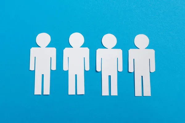 Top view of white paper cut people isolated on blue, team concept — Stock Photo