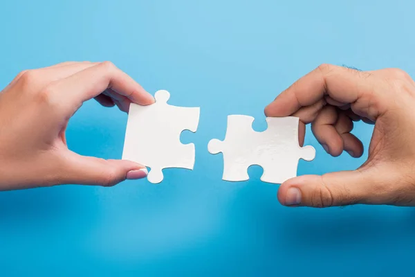 Cropped view of female and male hands with jigsaw on blue — Stock Photo