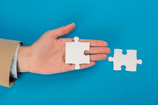 Top view of female hand near jigsaw on blue — Stock Photo