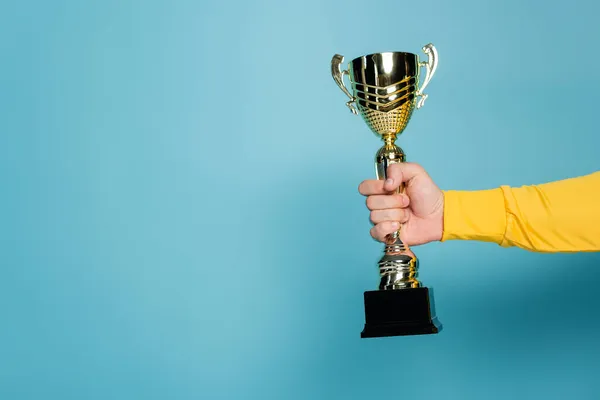 Cropped view of man holding golden trophy on blue — Stock Photo