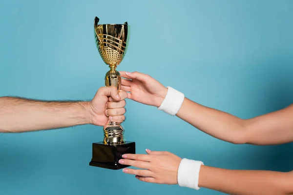 Cropped view of man giving golden trophy to female champion on blue — Stock Photo