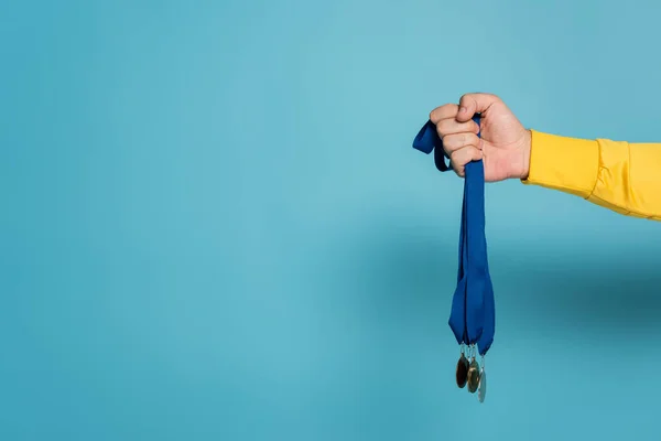 Partial view of champion holding medals on blue — Stock Photo