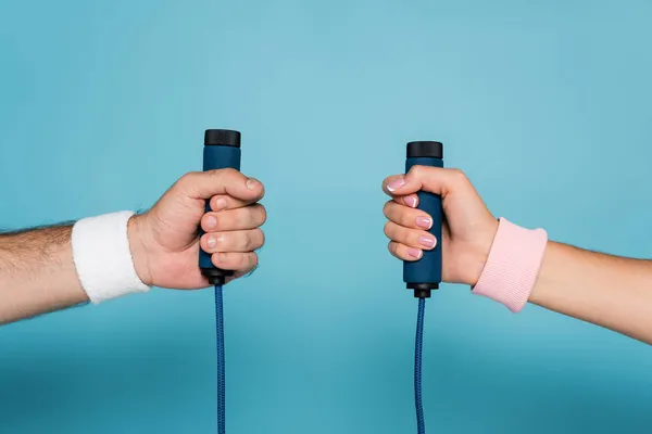 Cropped view of man and woman holding skipping rope on blue — Stock Photo