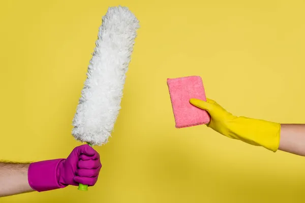 Cropped view of man and woman in rubber gloves holding cleaning supplies on yellow — Stock Photo