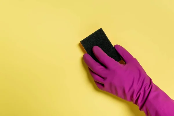 Partial view of cleaner in rubber glove holding sponge on yellow — Stock Photo