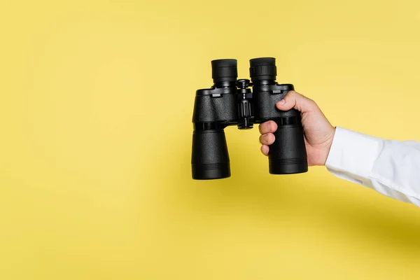 Vista cortada do homem segurando binóculos modernos pretos no amarelo — Fotografia de Stock