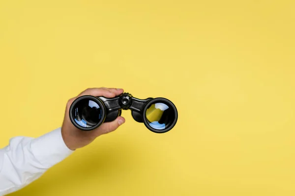 Vista recortada del hombre sosteniendo binoculares en amarillo — Stock Photo