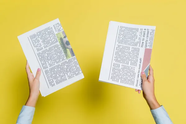 Cropped view of woman holding newspapers on yellow — Stock Photo