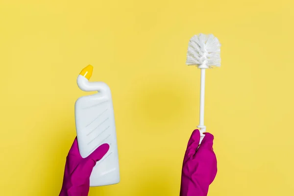 Vue partielle du nettoyant dans des gants en caoutchouc tenant bouteille avec détergent et brosse de toilette sur jaune — Photo de stock