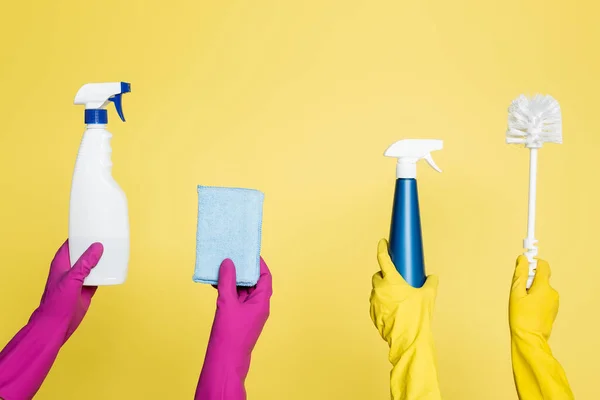 Vista cortada de produtos de limpeza segurando frascos de spray com detergente, pano e escova de vaso sanitário isolado em amarelo — Fotografia de Stock