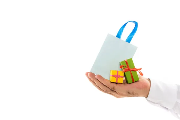 Vista recortada del hombre sosteniendo bolsa de compras y diminutas cajas de regalo aisladas en blanco - foto de stock