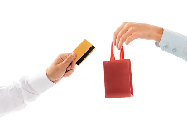 Vista ritagliata della donna che tiene la borsa della spesa vicino alla mano maschile con carta di credito isolata su bianco — Foto stock