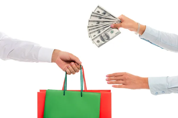 Обрезанный вид богатой женщины, держащей доллары банкноты возле мужской руки с пакетами для покупок изолированы на белом — стоковое фото