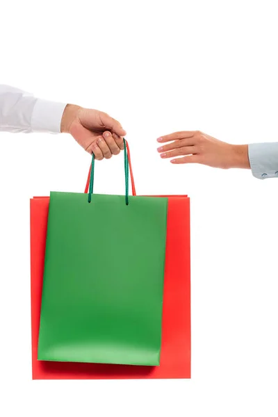 Vista recortada del hombre dando bolsas de compras a la mujer aislado en blanco - foto de stock