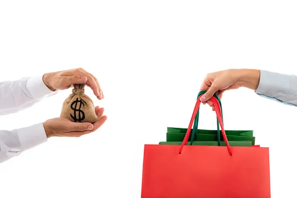 Vista ritagliata di uomo in possesso di denaro borsa vicino alla donna con shopping bags isolato su bianco — Foto stock