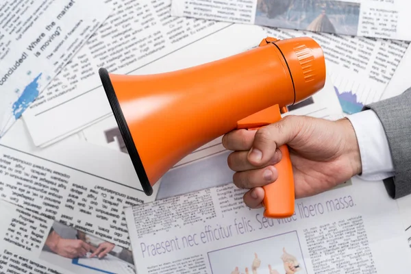 Top view of man holding megaphone above newspapers — Stock Photo