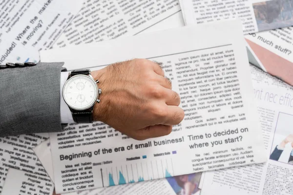 Vista superior del hombre de negocios mostrando reloj de pulsera por encima del periódico - foto de stock
