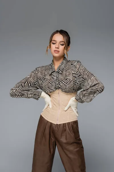 Stylish woman in blouse with zebra print posing with hands on hips isolated on grey — Stock Photo