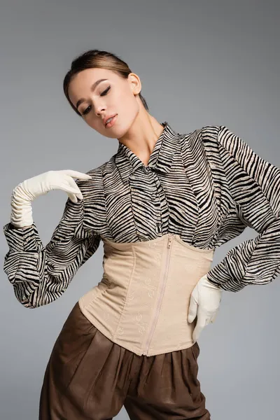 Jeune femme en chemisier imprimé animal, gants et corset posant isolé sur gris — Photo de stock