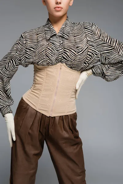 Vista recortada de mujer de moda en blusa con estampado animal, guantes y corsé posando aislados en gris - foto de stock