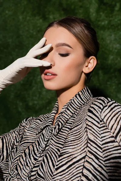 Mulher elegante em blusa com impressão zebra e luva branca posando perto de fundo gramado — Fotografia de Stock