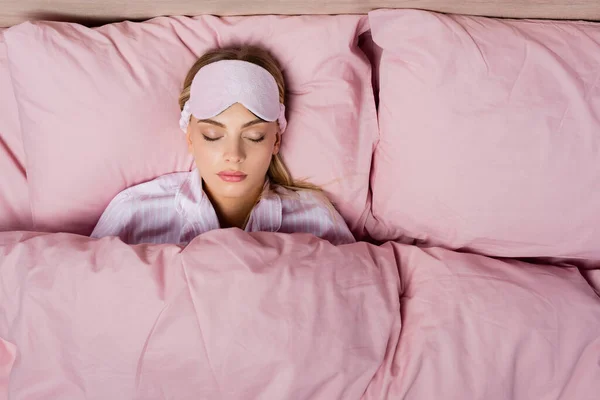 Top view of woman with mask sleeping on pink bedding at home — Stock Photo